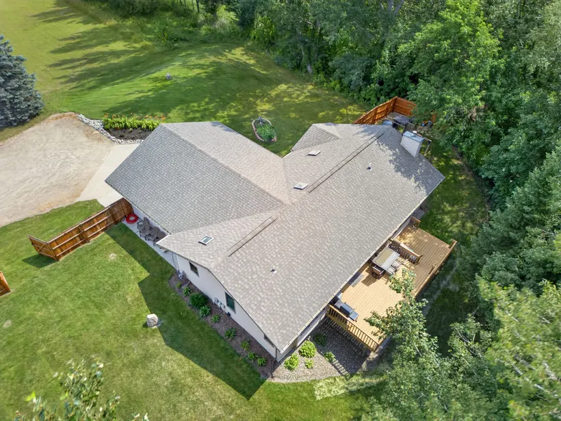 Aerial view over the roof toward the deck and wooded yard